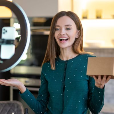 Young smiling beauty coach presenting new beauty products to online audience Beauty workshop. Young smiling beauty coach presenting new beauty products to online audience